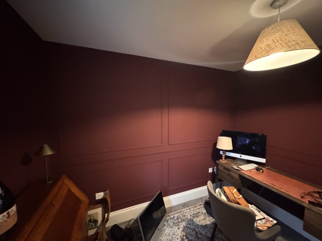 Burgundy panelled study with desk and lamp