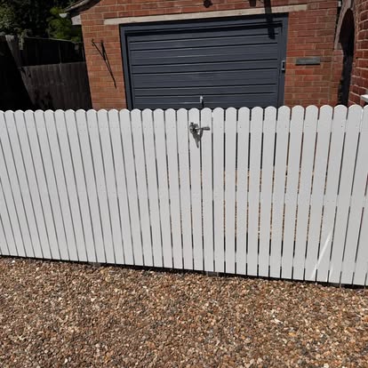 White painted fence and gate beside a garage