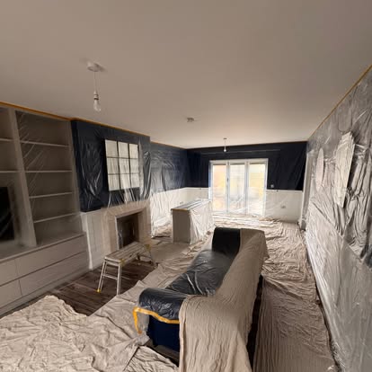 Living room protected with dust sheets while mural wallpaper is hung