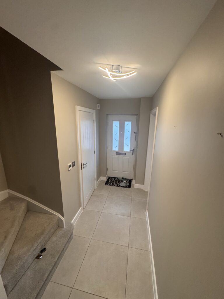 Long hallway painted in warm neutral leading to the front door