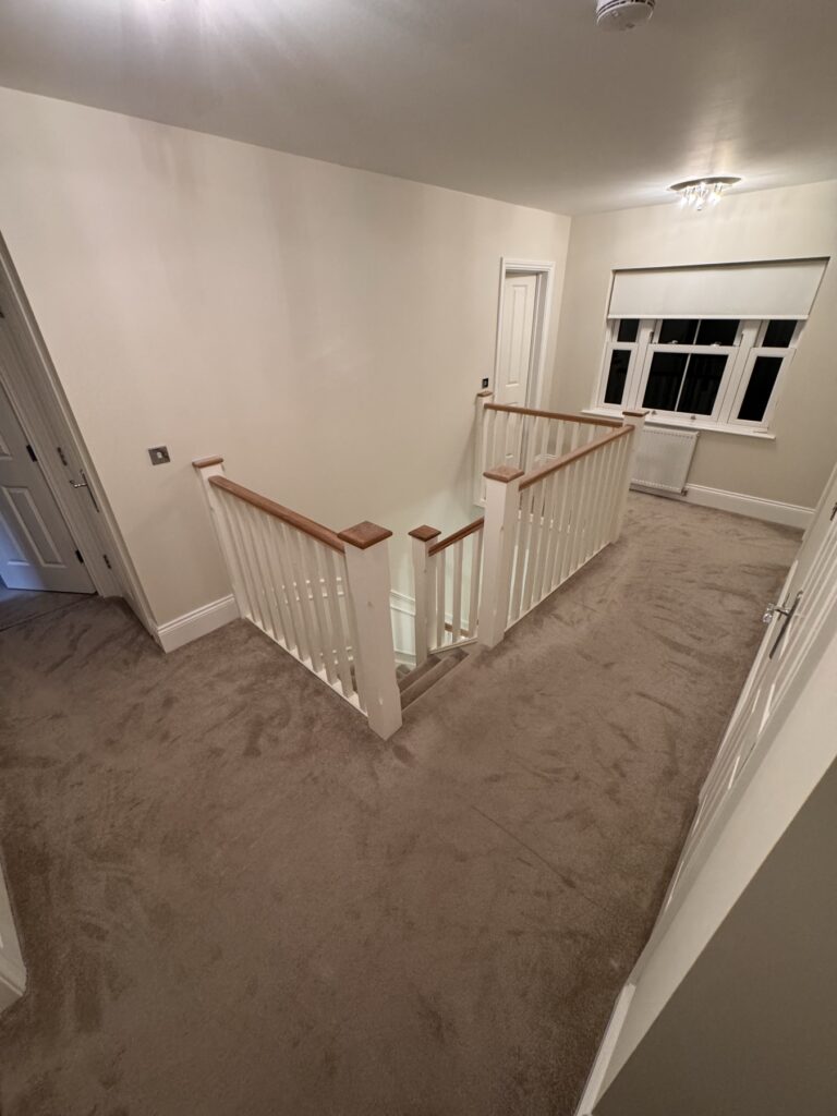 Landing with white spindles and oak handrail after decorating
