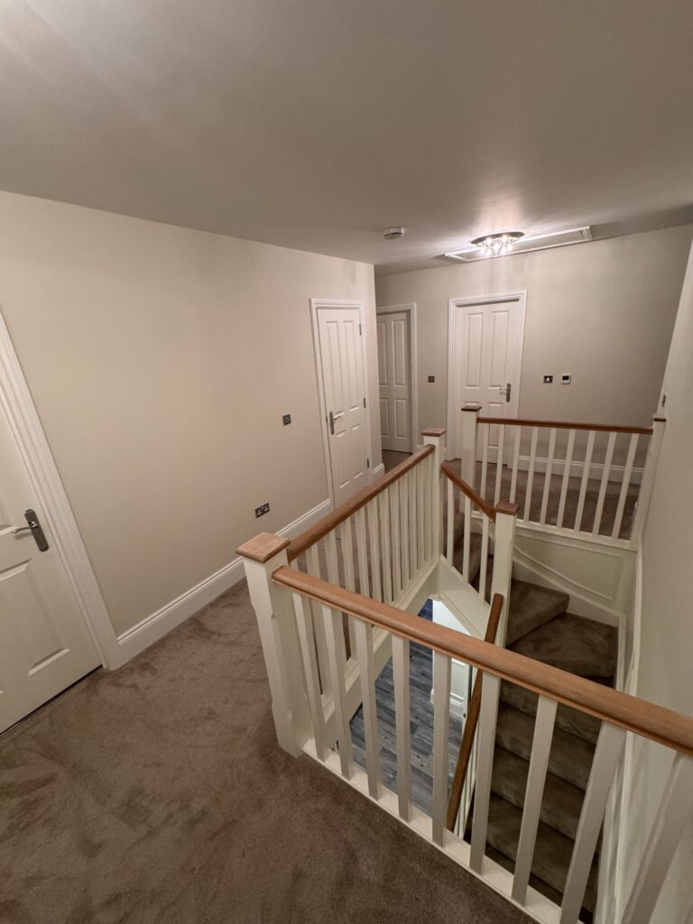 Bright landing and stairwell in warm neutral with white woodwork