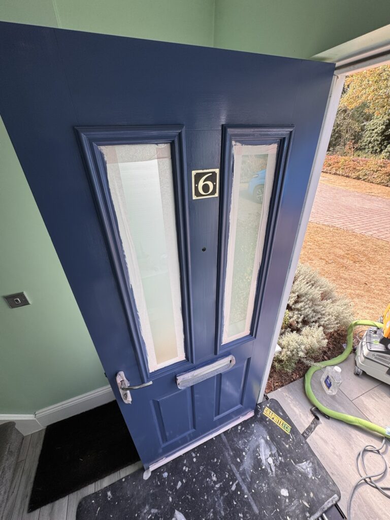 Composite front door freshly painted navy blue, masked for painting